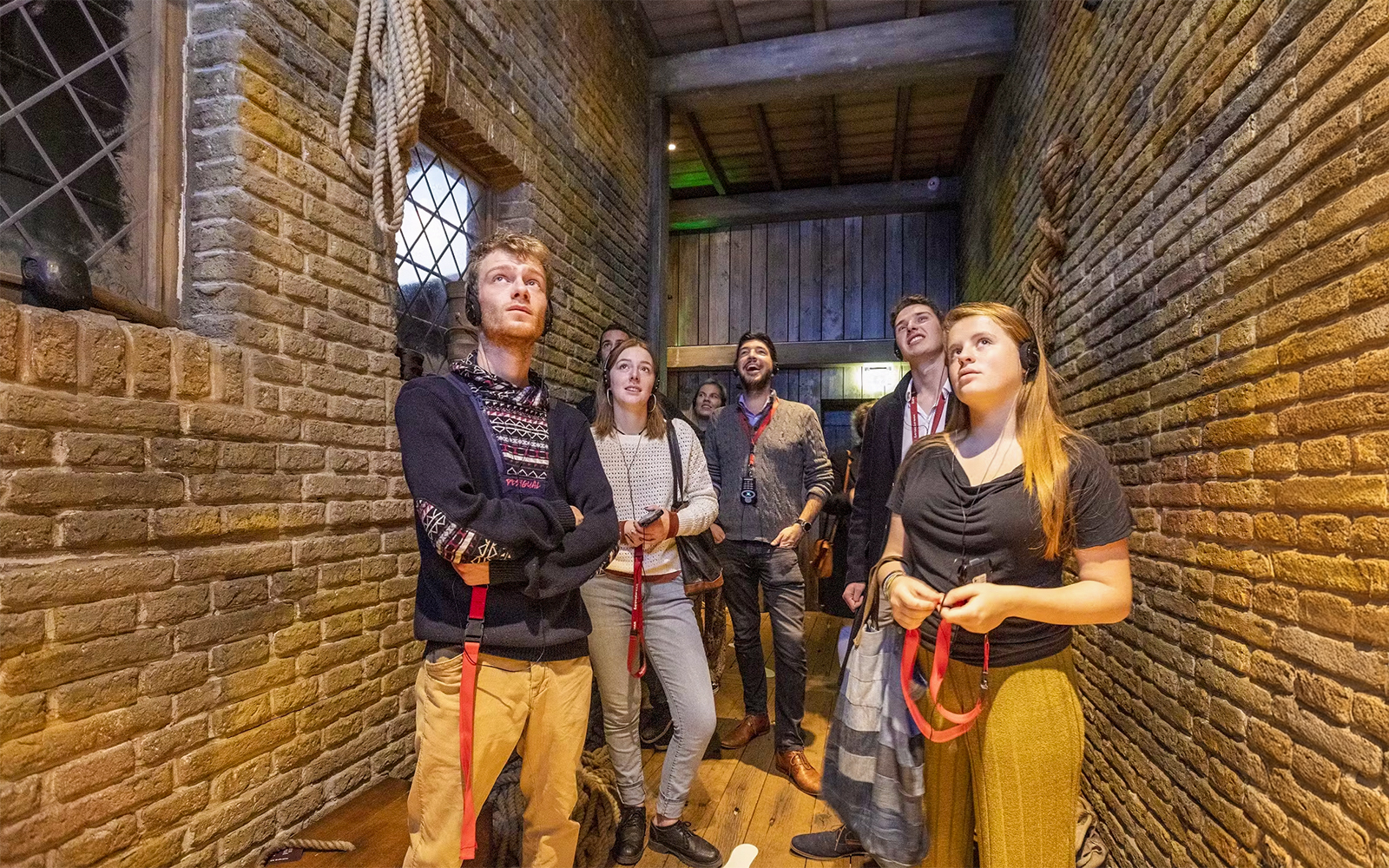 Visitors exploring an exhibit at Historium Bruges, wearing audio guides.