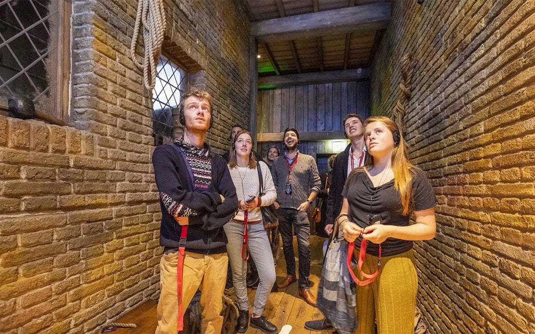 Visitors exploring an exhibit at Historium Bruges, wearing audio guides.