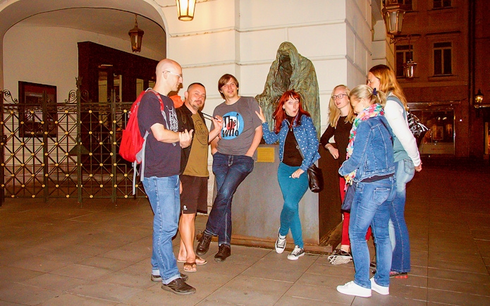 Tour guide explaining to tourists near a statue during Ghosts and Legends of Prague tour.