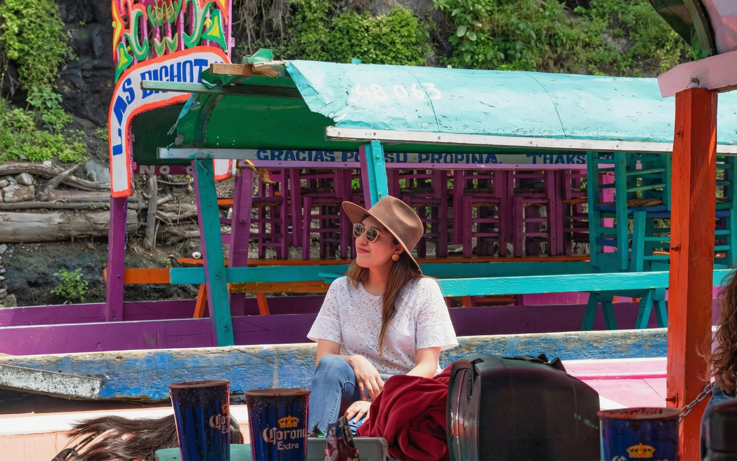Xochimilco trajinera with colorful decorations and a person enjoying the ride.