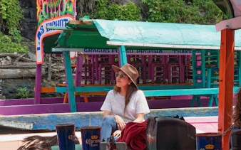 Xochimilco trajinera with colorful decorations and a person enjoying the ride.