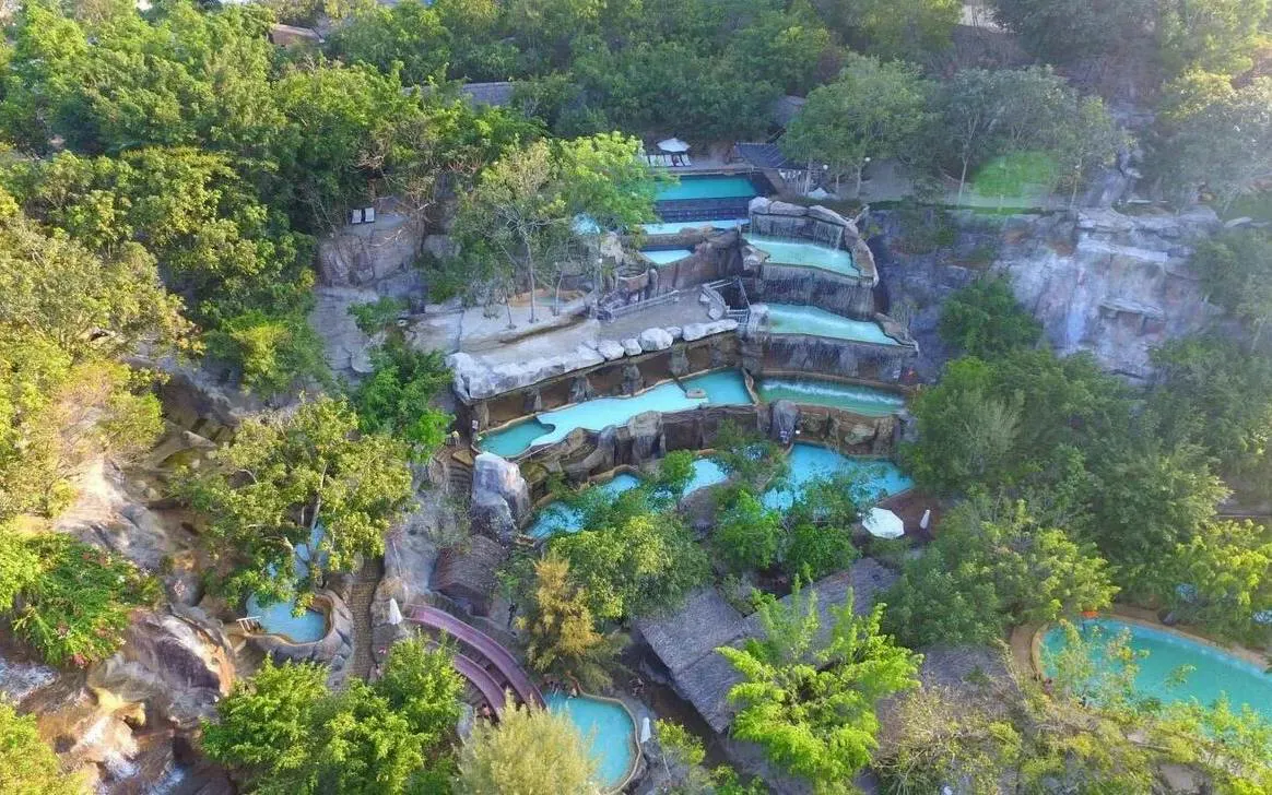 Aerial view of terraced pools surrounded by lush greenery at Cai River, Dubai.