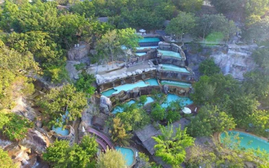 Aerial view of terraced pools surrounded by lush greenery at Cai River, Dubai.