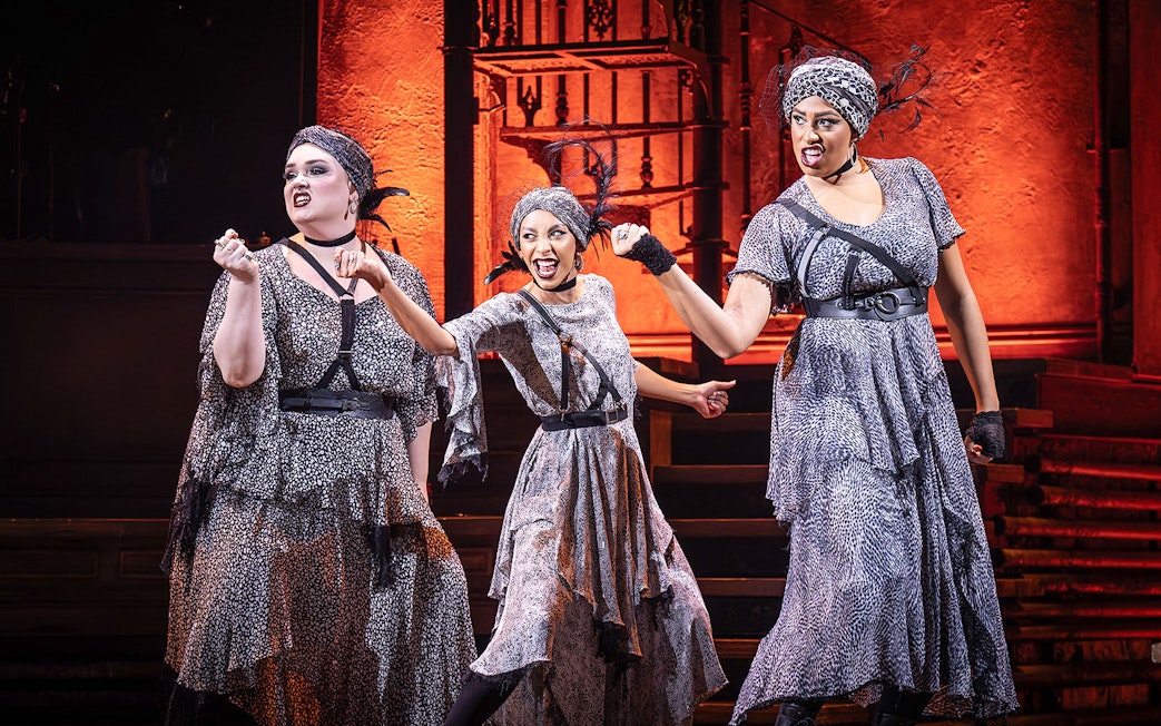 Performers in Hadestown musical on stage with dramatic expressions.