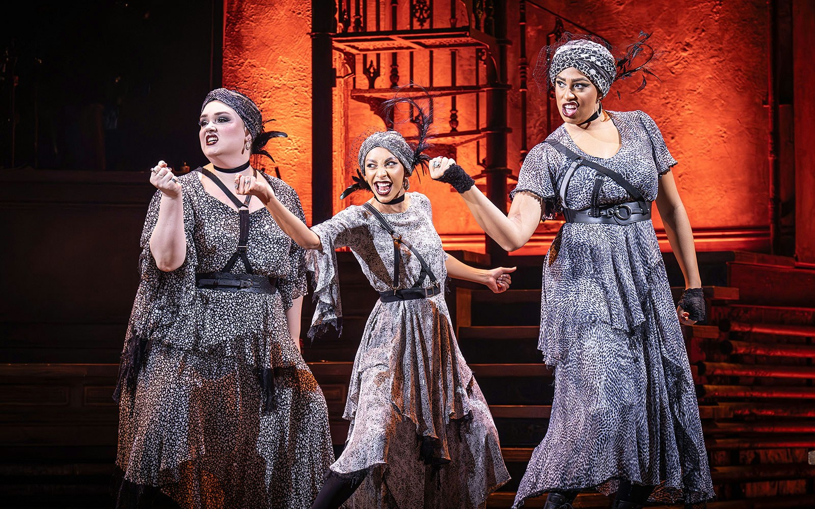 Performers in Hadestown musical on stage with dramatic expressions.