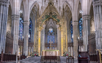 Stained glass windows and ornate altar inside St Patrick Cathedral, New York City.