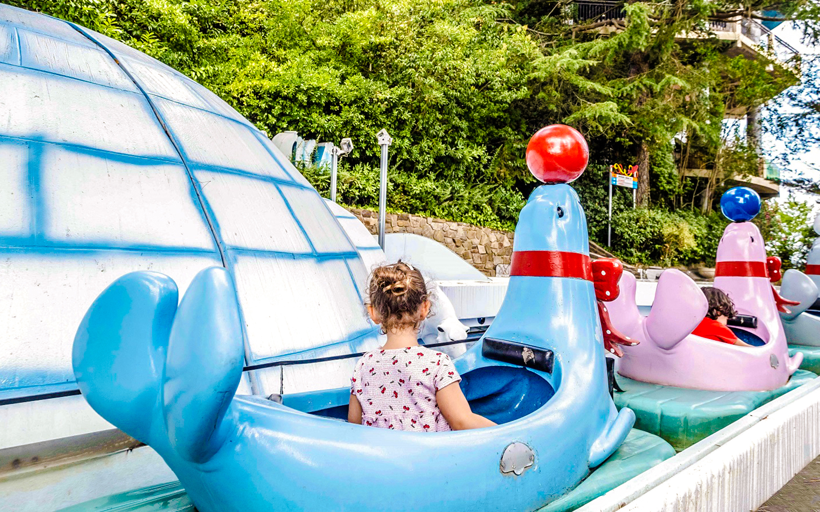 Children riding seal-shaped boats at Alaska ride, Tibidabo Amusement Park.