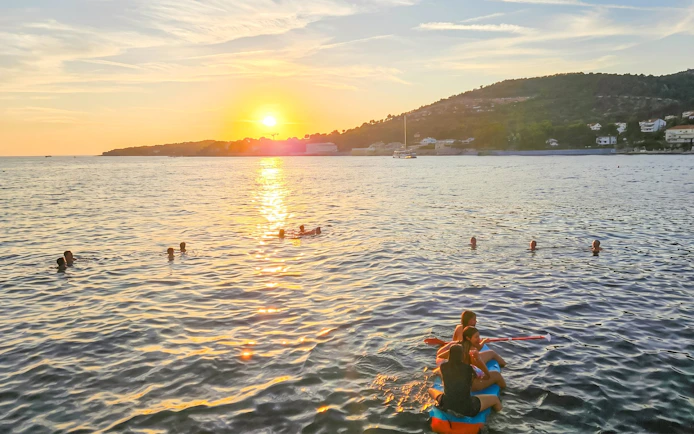 People enjoying a sunset catamaran cruise with apéritif, swimming in the sea.
