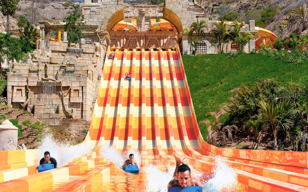 Water slide at Aqualand Maspalomas with people racing down on mats.