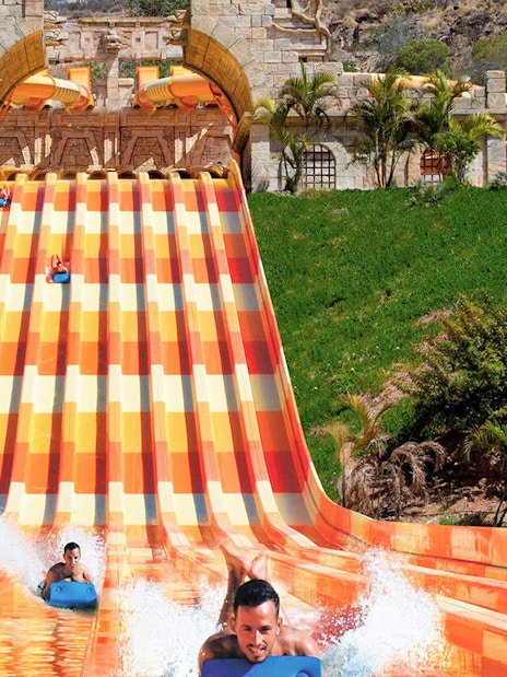 Water slide at Aqualand Maspalomas with people racing down on mats.