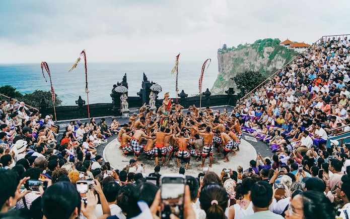 Kecak dance performance at Bali amphitheater with ocean view and audience.
