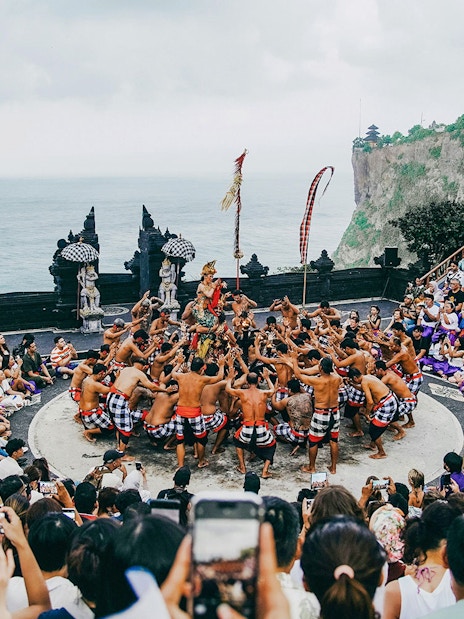 Kecak dance performance at Bali amphitheater with ocean view and audience.
