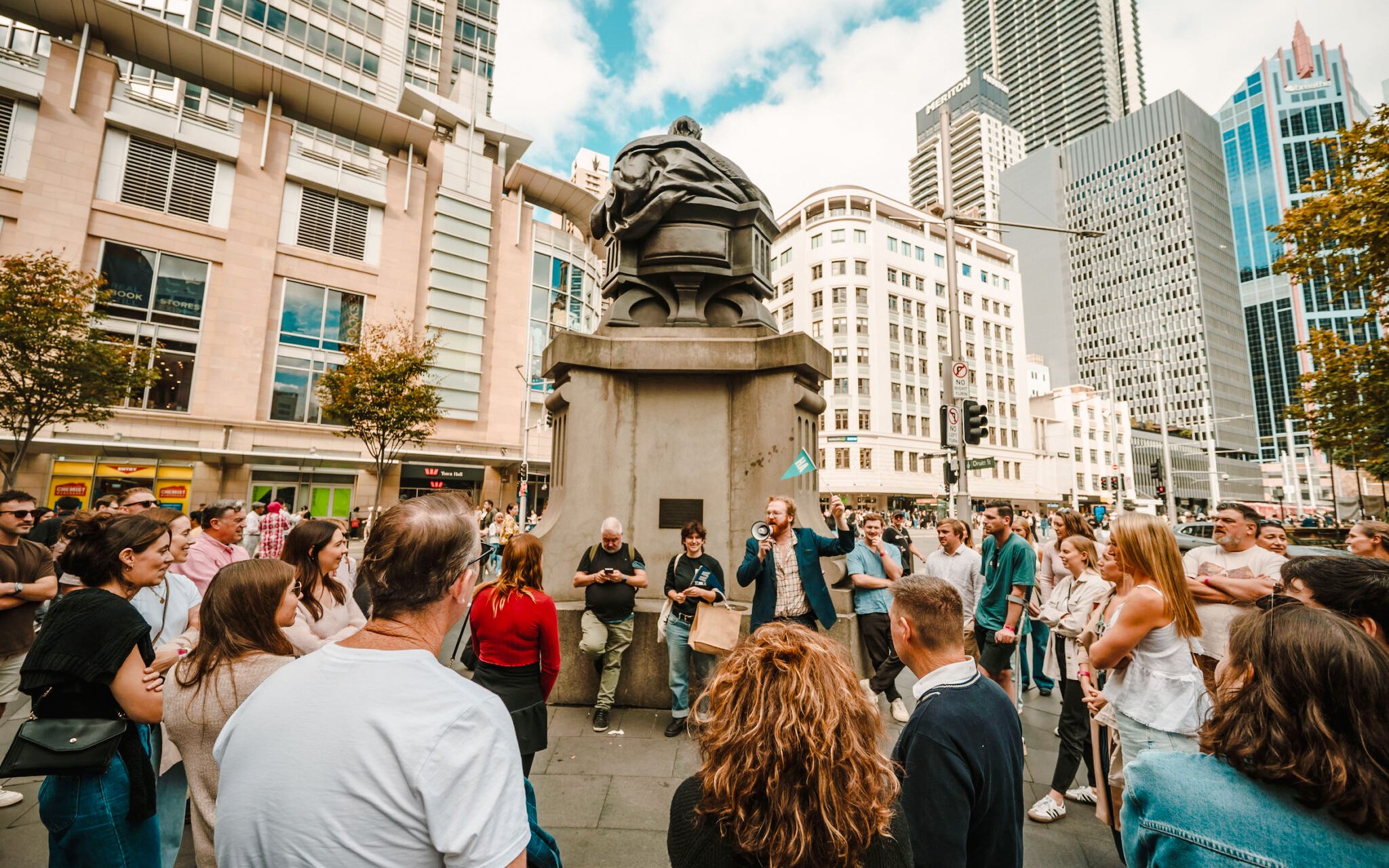 Crowd gathered around a speaker at Sydney Comedy Festival outdoor event.