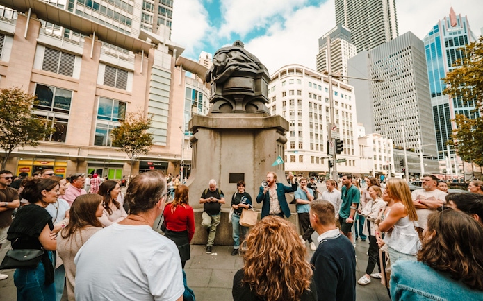 Crowd gathered around a speaker at Sydney Comedy Festival outdoor event.