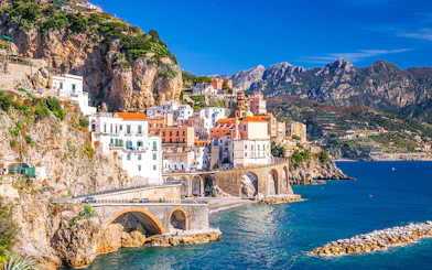 Coastal view of Sorrento, Italy, with colorful buildings on cliffs and tourists by the sea.