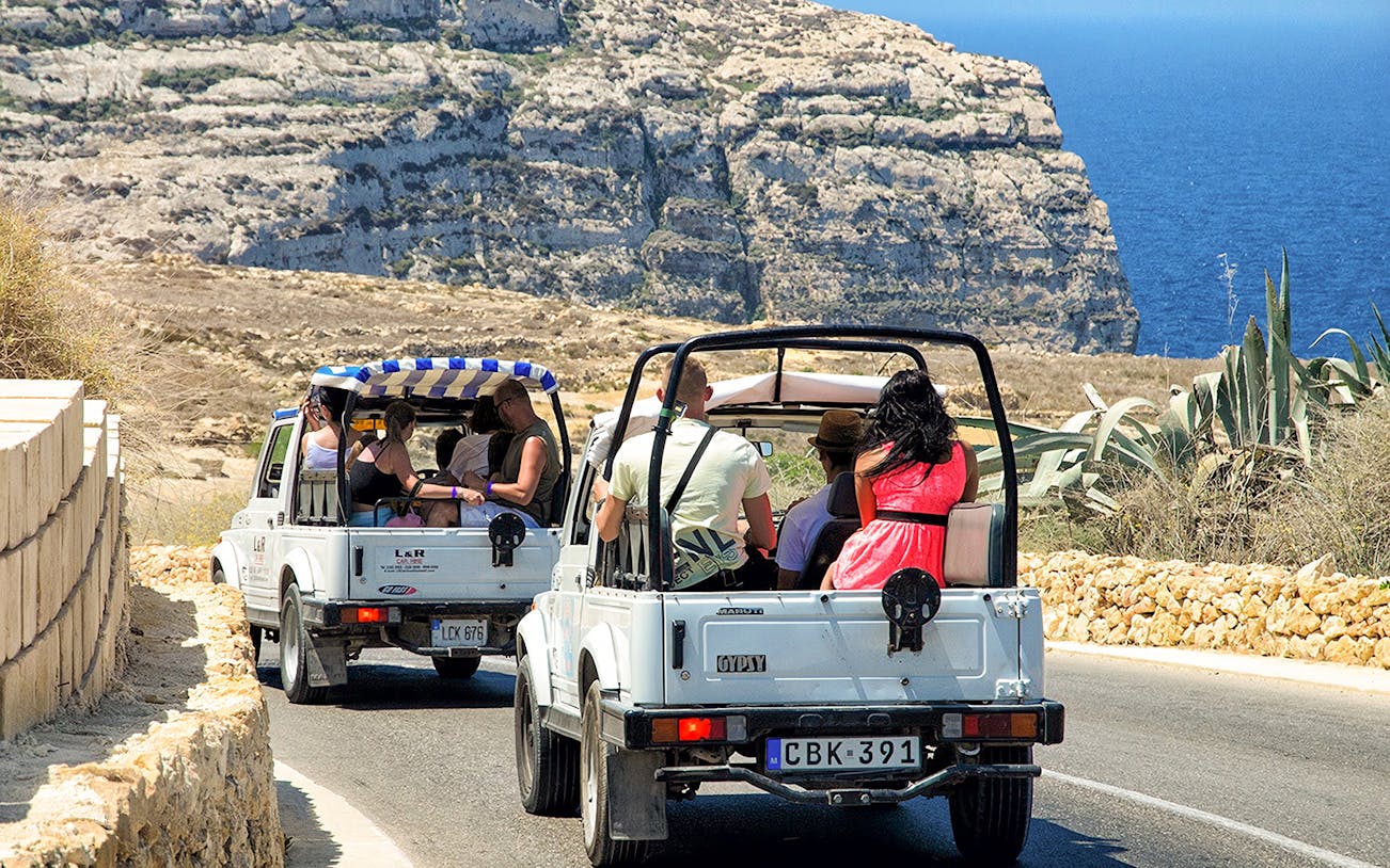 Jeep tour on Gozo island with passengers enjoying coastal views.