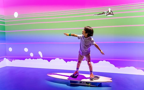 Child balancing on a surfboard simulator at the Australian Sports Museum.