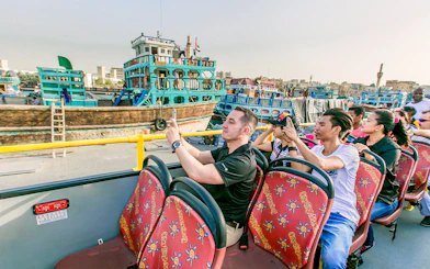 Tourists on a hop-on hop-off bus taking photos of Al Seef Dhow in Dubai.