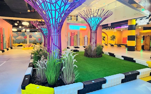 Neon-lit driving course with tree-like sculptures at VroomTown Driving City.