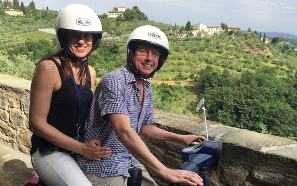 Couple riding a Vespa through the Tuscan countryside on a guided tour from Florence.