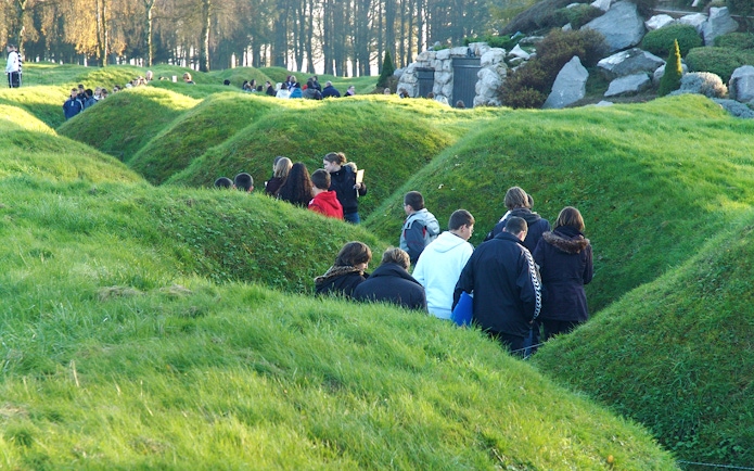 Visitors exploring grassy trenches at Somme battlefields on a day trip from Paris.