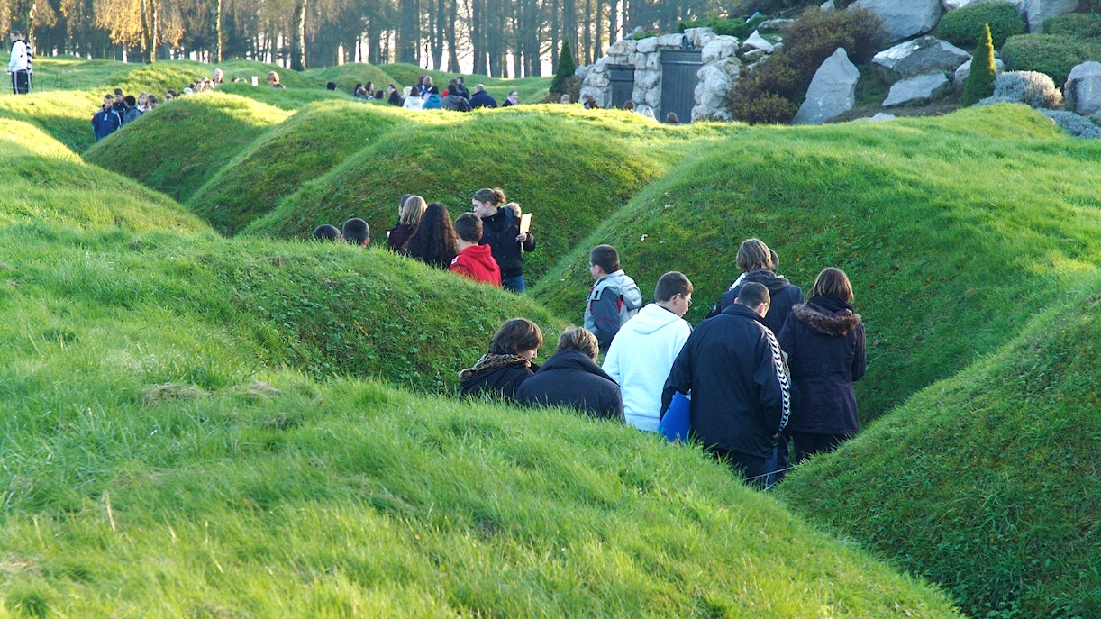Visitors exploring grassy trenches at Somme battlefields on a day trip from Paris.