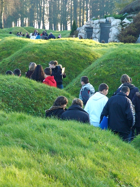 Visitors exploring grassy trenches at Somme battlefields on a day trip from Paris.