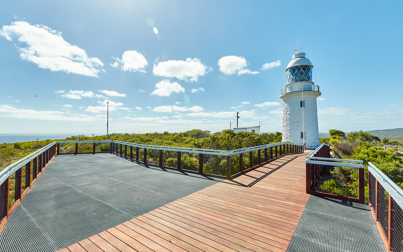 Boardwalk leading to Cape Naturaliste Lighthouse under sunny sky, Western Australia.