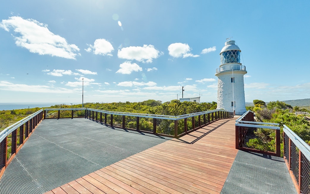 Boardwalk leading to Cape Naturaliste Lighthouse under sunny sky, Western Australia.