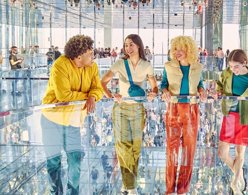 Four people standing on mirrored floor at SUMMIT One Vanderbilt, New York City.