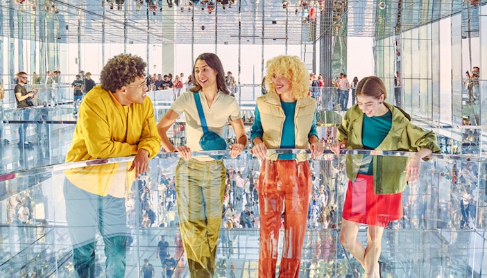 Four people standing on mirrored floor at SUMMIT One Vanderbilt, New York City.
