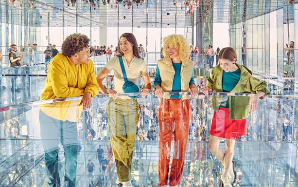 Four people standing on mirrored floor at SUMMIT One Vanderbilt, New York City.