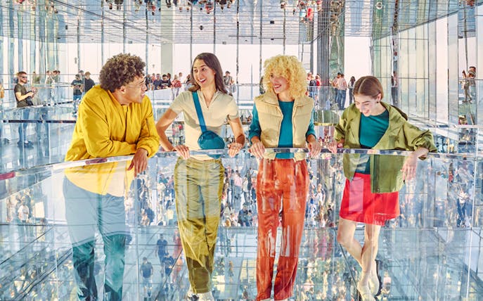 Four people standing on mirrored floor at SUMMIT One Vanderbilt, New York City.