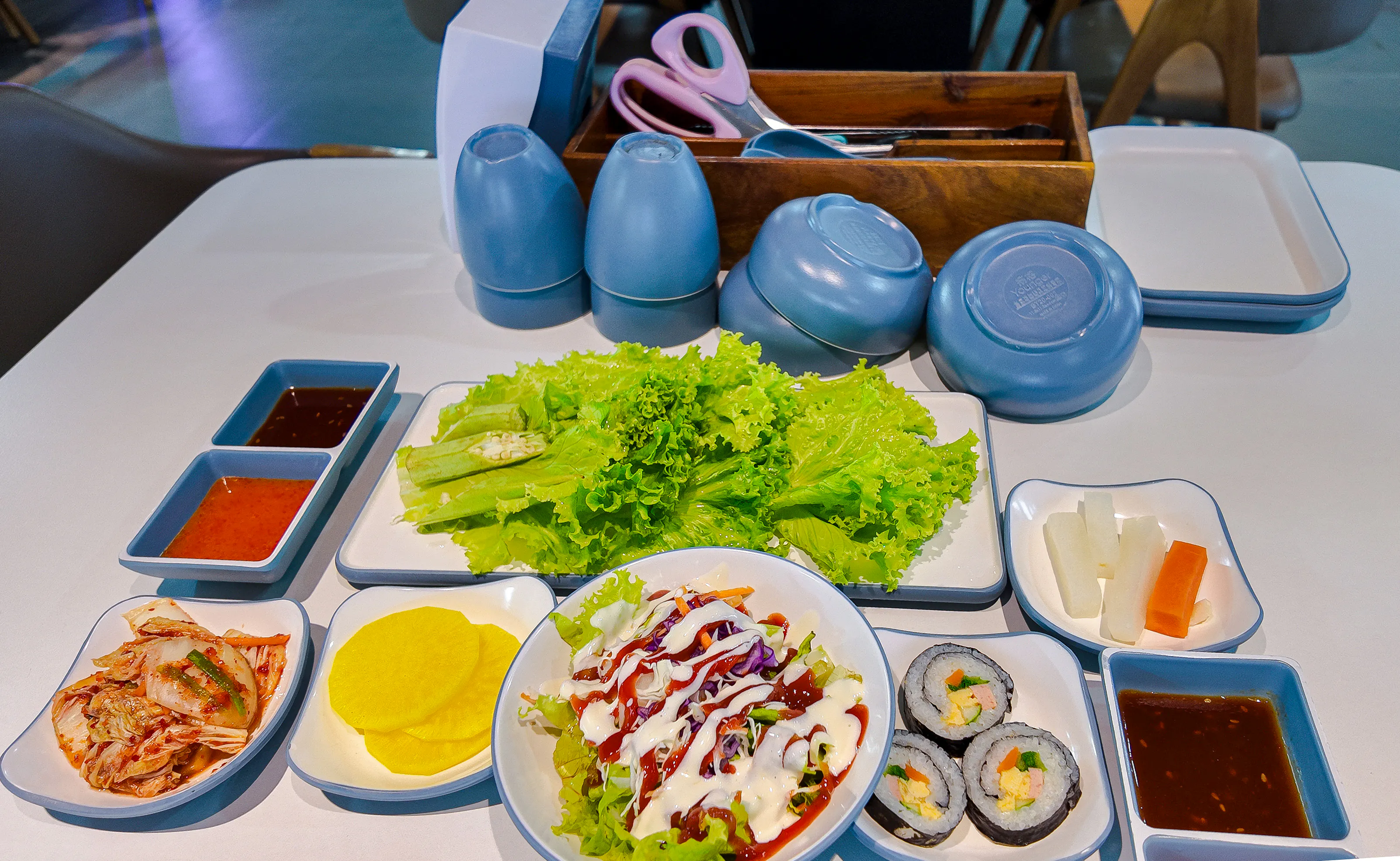 Korean BBQ side dishes with lettuce, kimchi, pickled radish, and sushi rolls on Phu Quoc Sunset Tour.
