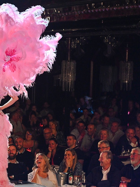 Performers on stage at Paradis Latin cabaret in Paris, with audience watching.