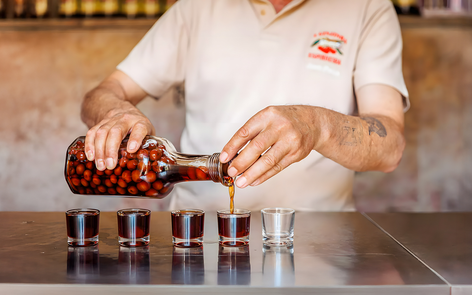 Pouring cherry liqueur into glasses during Lisbon Food Walk in Baixa.
