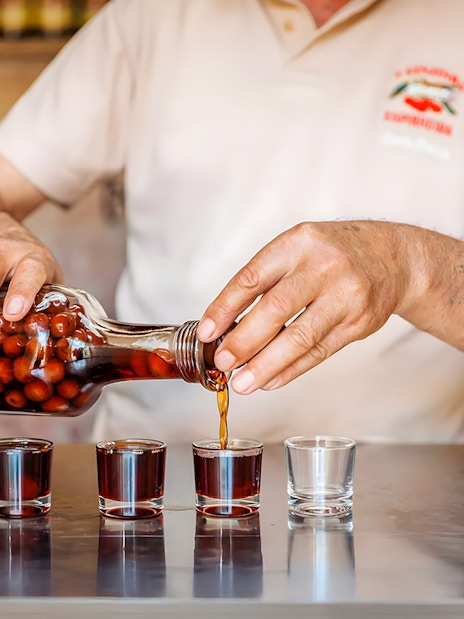 Pouring cherry liqueur into glasses during Lisbon Food Walk in Baixa.