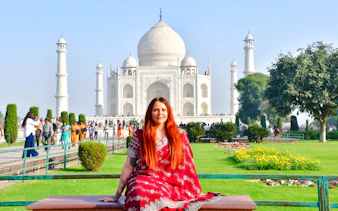 Sunrise view of the Taj Mahal with a visitor in traditional attire, Agra tour.