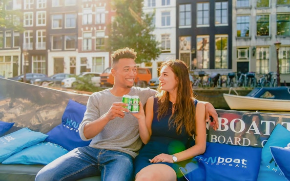 Guests enjoying drinks on an open boat cruise in Amsterdam canal.