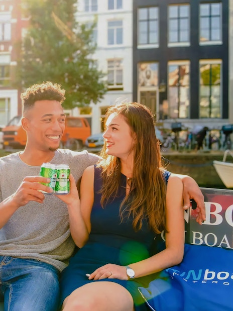 Guests enjoying drinks on an open boat cruise in Amsterdam canal.