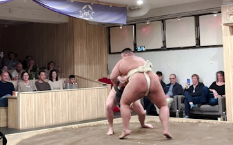 Sumo wrestlers competing in a ring with an audience in Shibuya, Tokyo.