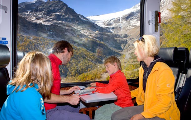 Family enjoying scenic views on the Bernina Express in Switzerland with Interrail pass.