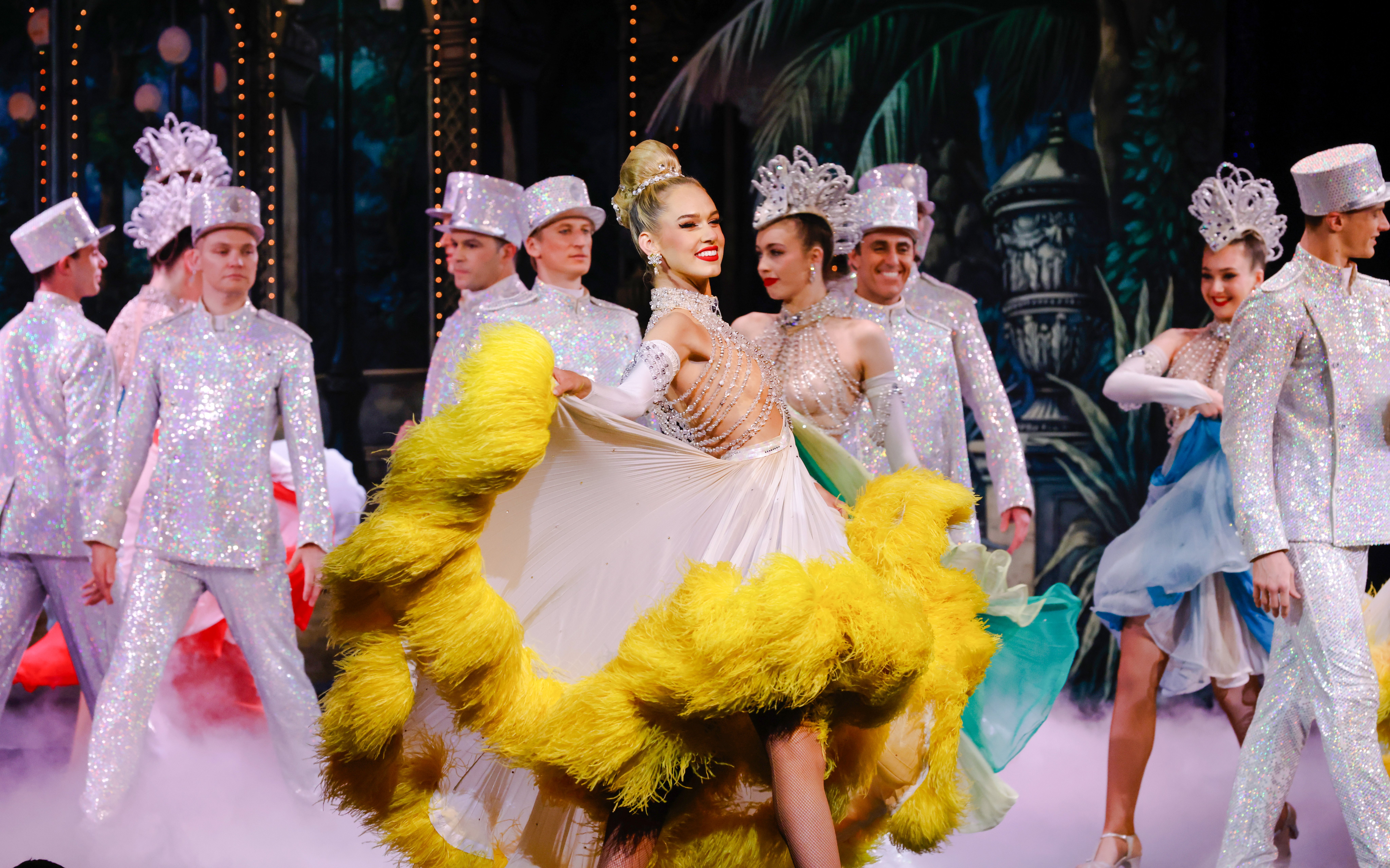 Performers in vibrant costumes dancing at the Moulin Rouge show in Paris.