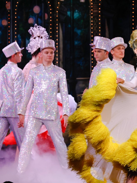 Performers in vibrant costumes dancing at the Moulin Rouge show in Paris.