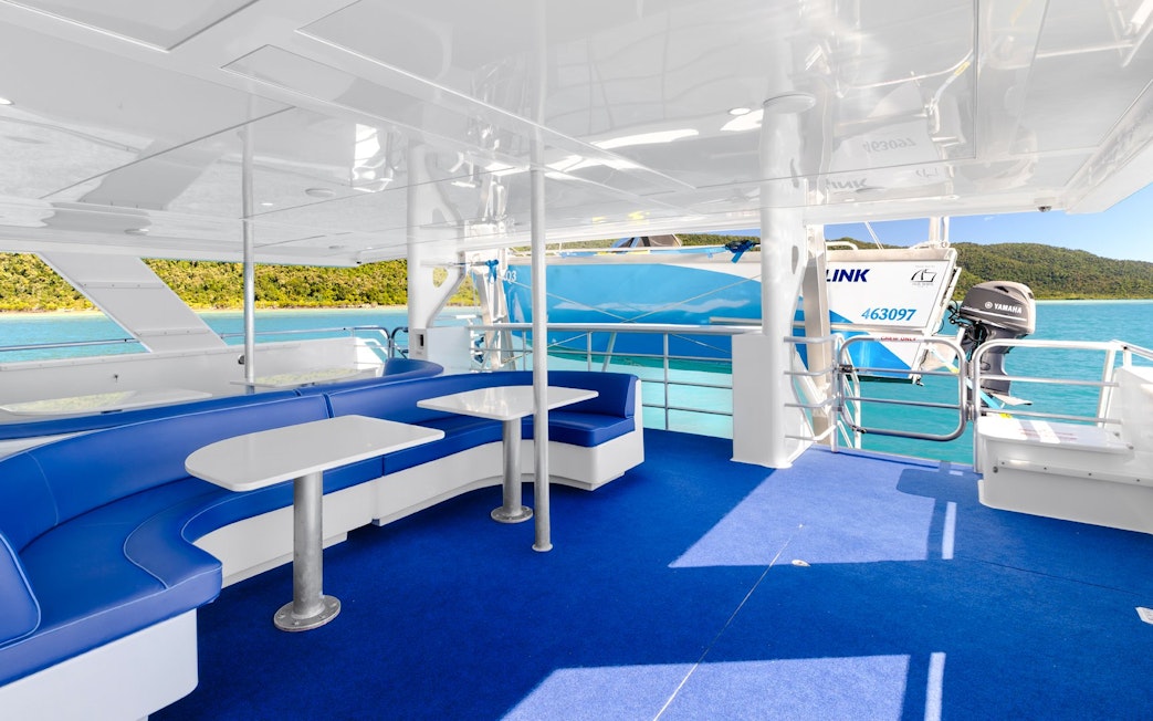 Interior of a cruise boat with seating, overlooking turquoise waters near Airlie Beach.