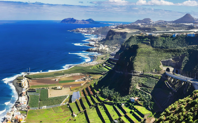 Rocky coastline and terraced green slopes along the north coast of Gran Canaria, Canary Islands, Spain.