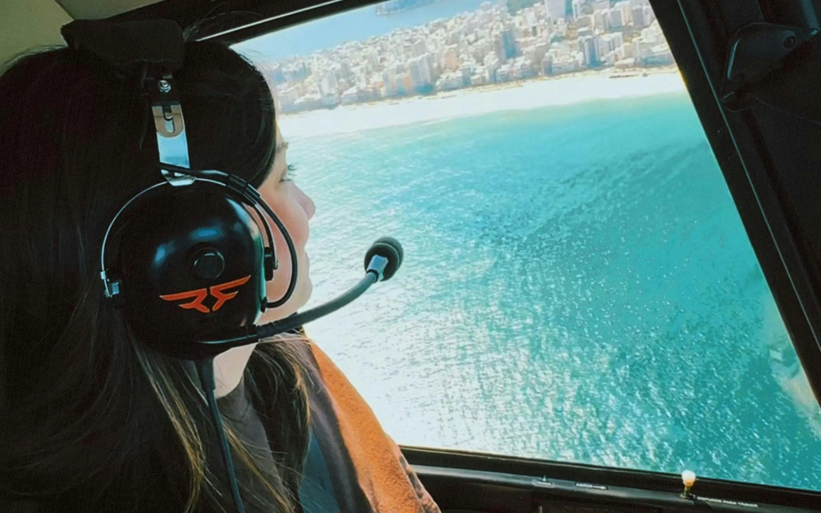 Tourist enjoying aerial view of Rio de Janeiro coastline from helicopter.