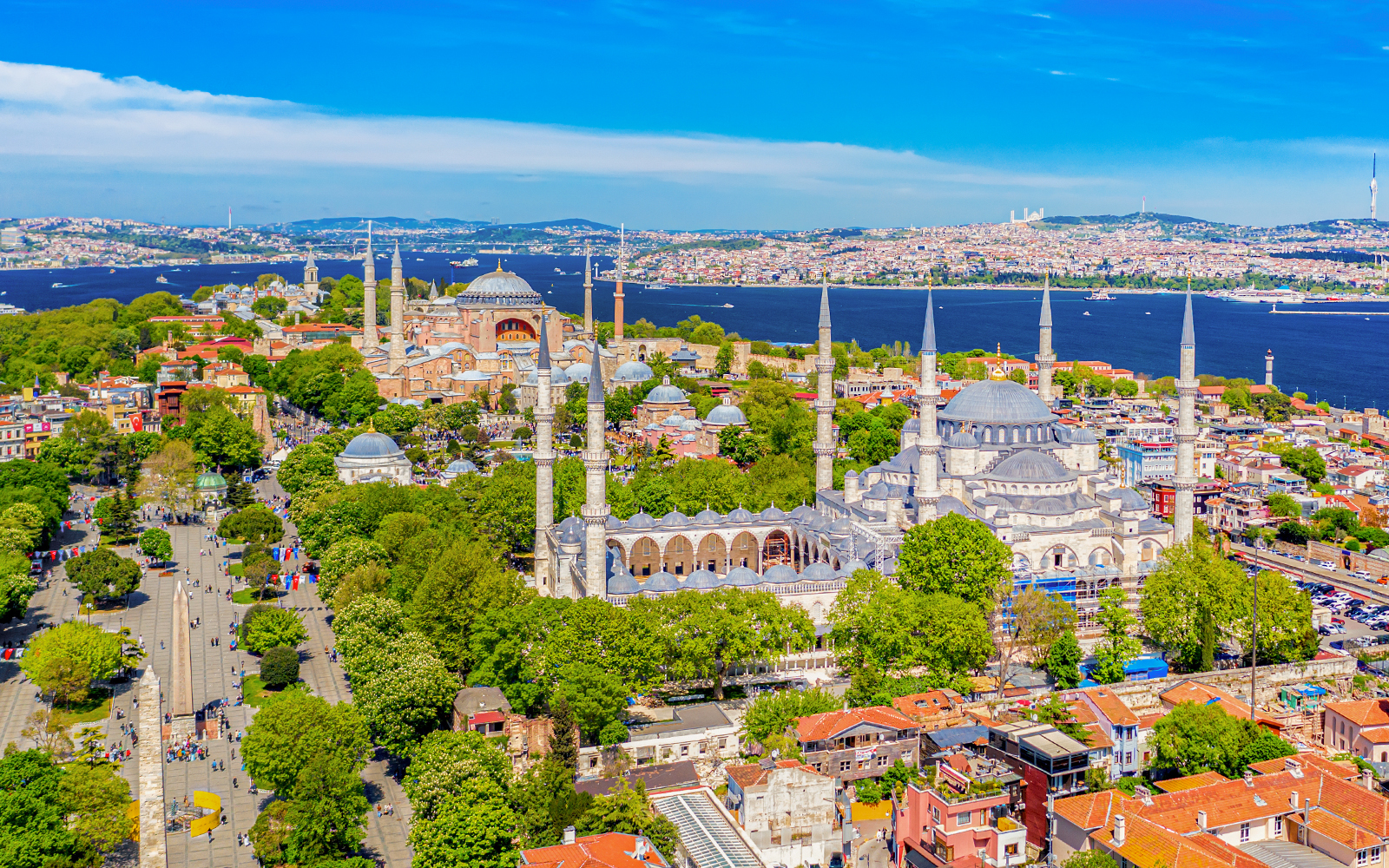 Hagia Sophia and Blue Mosque in Sultanahmet district, Istanbul, with tourists exploring the historic architecture.