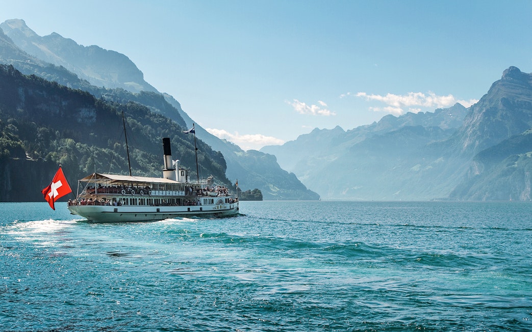 Steamboat on Lake Brienz with Swiss flag, surrounded by mountains in Berner Oberland.