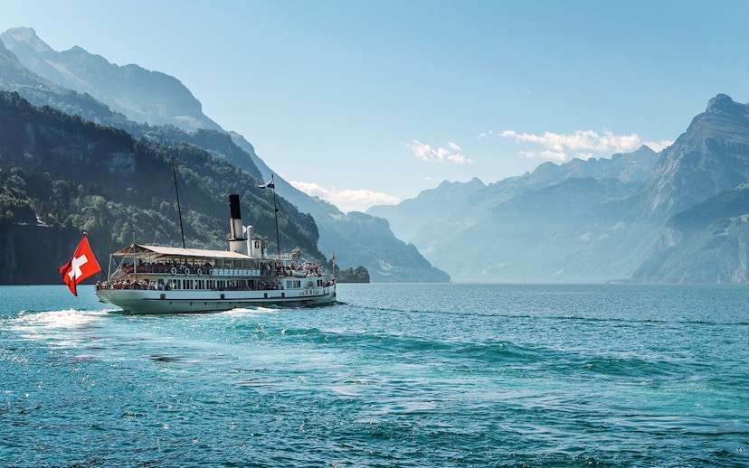 Steamboat on Lake Brienz with Swiss flag, surrounded by mountains in Berner Oberland.